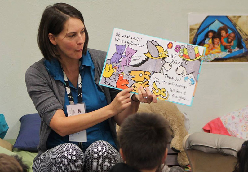 A volunteer reads a book to a group of students during Read Aloud. 